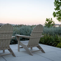 Outdoor chairs on a paved patio surrounded by garden planting