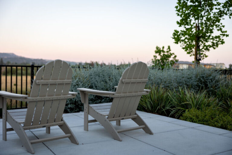 Outdoor chairs on a paved patio surrounded by garden planting